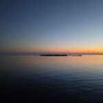 At sunrise, the horizon whispers new beginnings across a still sea.